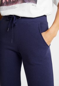 Mörkblå sweatpants i mjukt tyg, med elastisk midja, snörning och sidofickor med en slät yta.