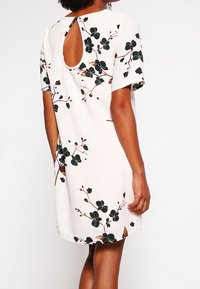 Kortärmad blommig klänning i krämfärg med mörkgröna och bruna detaljer, med en design med nyckelhål på baksidan och en avslappnad passform.