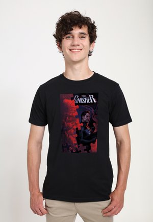 Sort t-shirt med et farverigt grafisk tryk af "The Punisher", med fede røde og mørkeblå nuancer, omgivet af en puslespils-kant.
