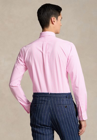 Πουκάμισο με slim γραμμή και μακριά μανίκια σε ανοιχτό ροζ χρώμα με λεπτές λευκές ρίγες. Διαθέτει κλασικό γιακά και μανσέτες με κουμπιά. Οριζόντια ραφή στους ώμους.