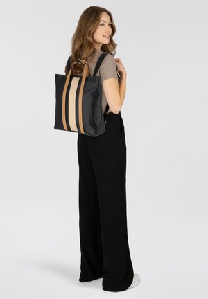 Sac fourre-tout noir avec deux bandes verticales beiges, fabriqué en matériau lisse. Doté de poignées marron et de bretelles réglables.