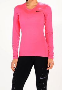 Long-sleeve athletic shirt in bright pink, made of lightweight, stretchy material, featuring a small black Nike logo on the left chest.