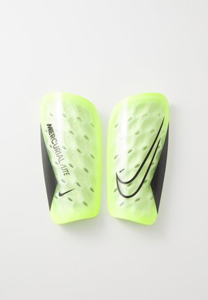 Espinilleras Nike Mercurial Lite, de un brillante color amarillo con un patrón hexagonal texturizado, que presentan un acento negro y el logo en el costado.