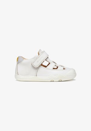 Sandalia blanca de cuero para niños pequeños con tiras de velcro, costados recortados y suela de goma flexible.