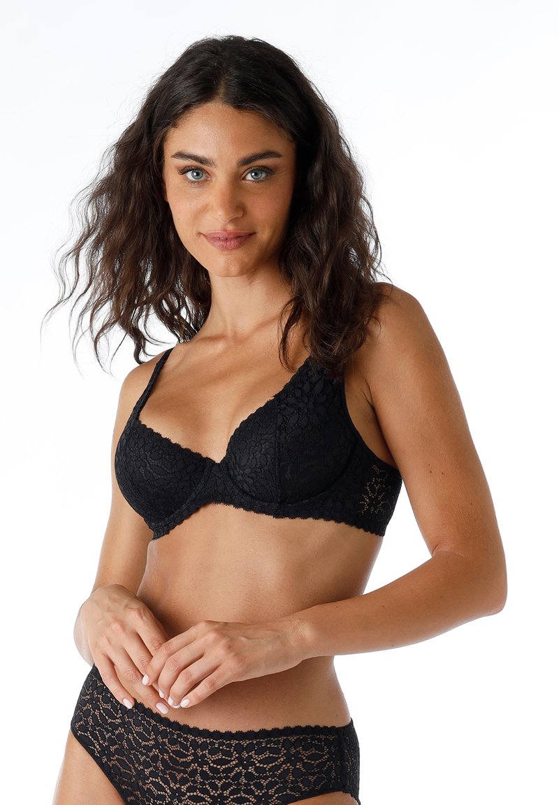 Reggiseno in pizzo nero con scollatura a V, supporto con ferretto, spalline regolabili e delicati motivi floreali; abbinato a mutandine in pizzo coordinate.