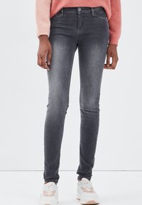 Jeans skinny de color gris oscuro, hechos de denim con un ligero estiramiento, que presentan un diseño clásico de cinco bolsillos y un cierre frontal con botón.