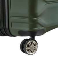 Valigia rigida con superficie verde testurizzata, dettagli neri e una ruota girevole argentata con design a 5 razze.
