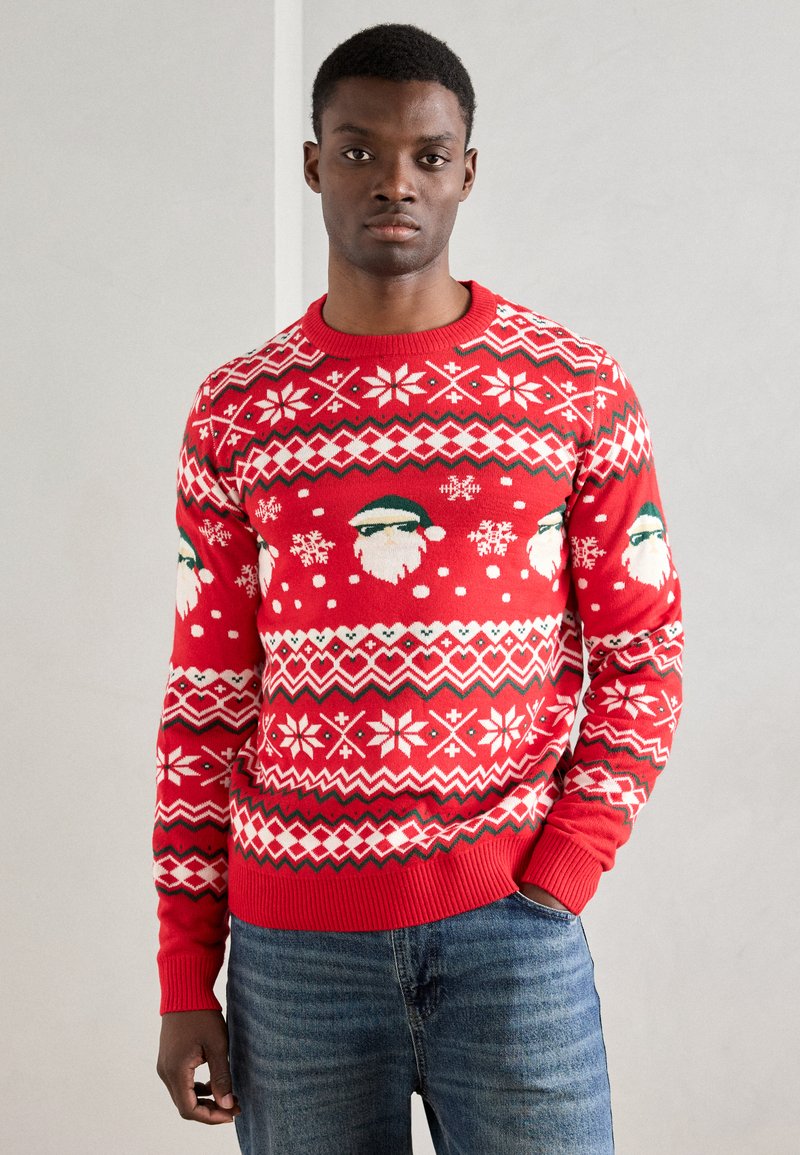 Roter gestrickter Pullover mit einem Muster aus weißen Schneeflocken, Santa-Gesichtern und geometrischen Designs. Gerippter Halsausschnitt und Bündchen.