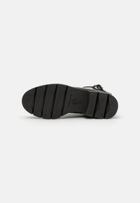 Sole di scarpa in gomma nera con un motivo testurizzato, forma curva e distintivi tacchi segmentati per la trazione. Taglia contrassegnata come 37.