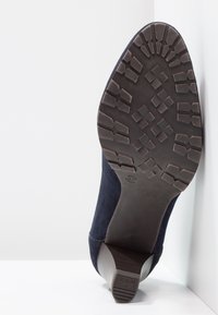 Námořnické semišové boty na podpatku s texturovanou gumovou podrážkou a podešví s listovým vzorem. Obsahují zakřivený podpatek a design kulaté špičky.