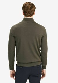 Olivgrön, stickad tröja med ribbad krage och ärmslut. Har en figurnära design och en slät, strukturerad yta.