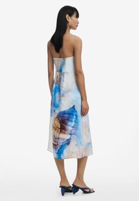 Õlatu merr, kus on värvikas kooreprint sinises ja beežis. Valmistatud siledast kangast, millel on ülikitsas, volangiga korpus ja voolav seelik.