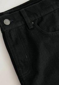 Jeans in denim nero con una texture liscia, chiusura a bottone argentato e tasche frontali inclinate. Cuciture tonali distintive e linee pulite.