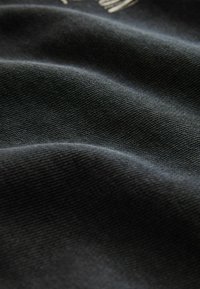 Material textil negru, cu o textură moale și pliuri fluente. O privire de aproape evidențiază modelul țesăturii și suprafața netedă. Potrivit pentru îmbrăcăminte sau tapițerie.