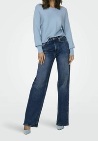 Light blue ribbed sweater paired with dark blue wide-leg jeans, showcasing a relaxed fit and rolled cuffs. Soft fabric and minimalist design.