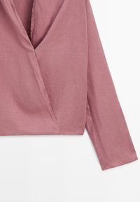 Blusa in lino color rosa pesca a maniche lunghe con davanti incrociato e scollo a V, mostrata su uno sfondo bianco piatto.