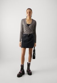 Gray ribbed wrap top, black denim miniskirt with frayed hem, ankle-length black and purple boots, and a small black handbag.