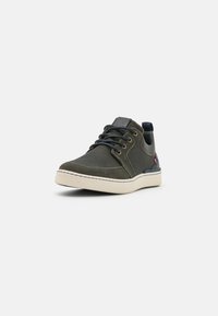 Olive green sneaker with a textured fabric upper, navy accents, round laces, and a light-colored rubber sole. Features a branded detail on the side.
