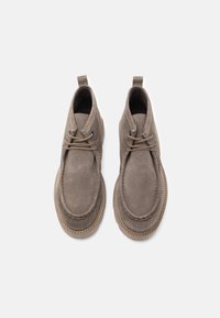 Botas de tobillo de ante gris con punteras redondeadas, costuras beige y un cordón mínimo. Presentan una lengüeta en el talón para facilitar el calzado. Textura suave.