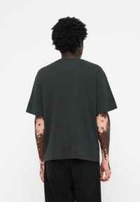 Dark gray oversized t-shirt with a crew neck, short sleeves, and a relaxed fit, made from soft cotton blend fabric.