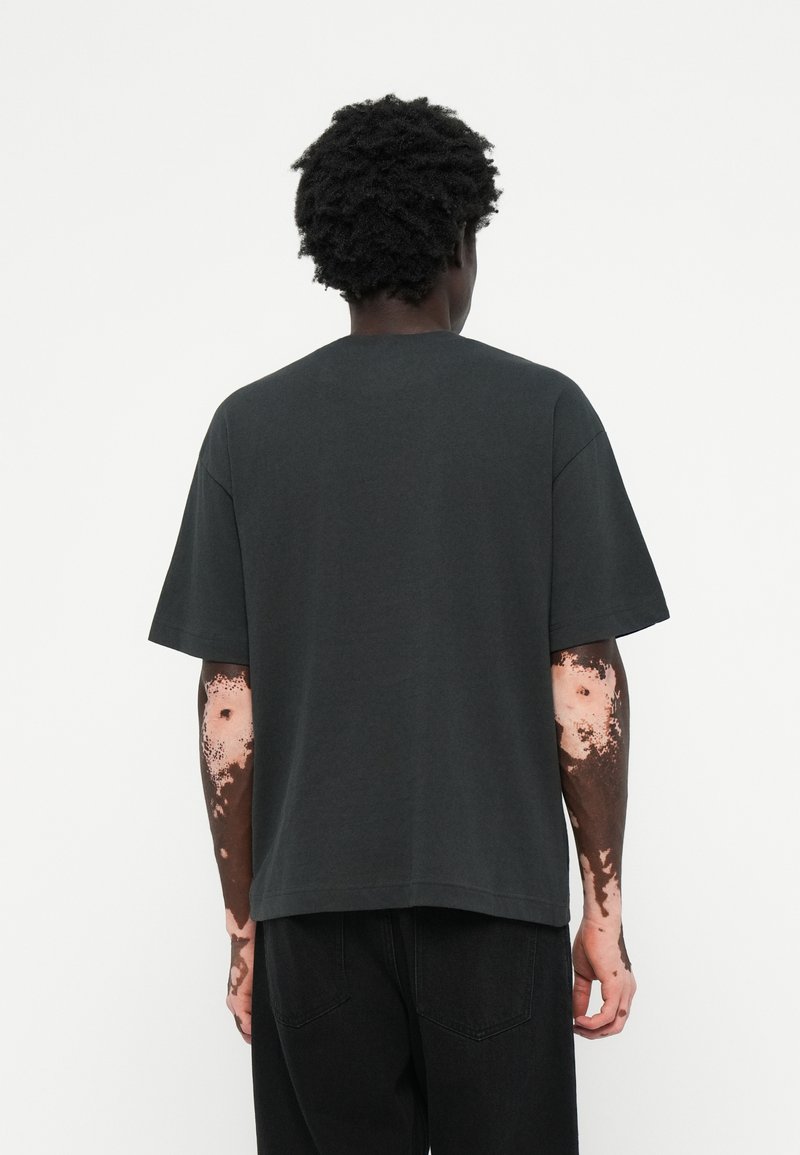 Dunkelgraues, übergroßes T-Shirt mit Rundhalsausschnitt, kurzen Ärmeln und lockerer Passform, aus weichem Baumwollmischgewebe gefertigt.