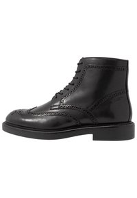 Černé kožené kotníkové boty s kulatou špičkou, brogue detaily, šněrovacím designem a silnou černou gumovou podrážkou. Hladký povrch, lesklý vzhled.