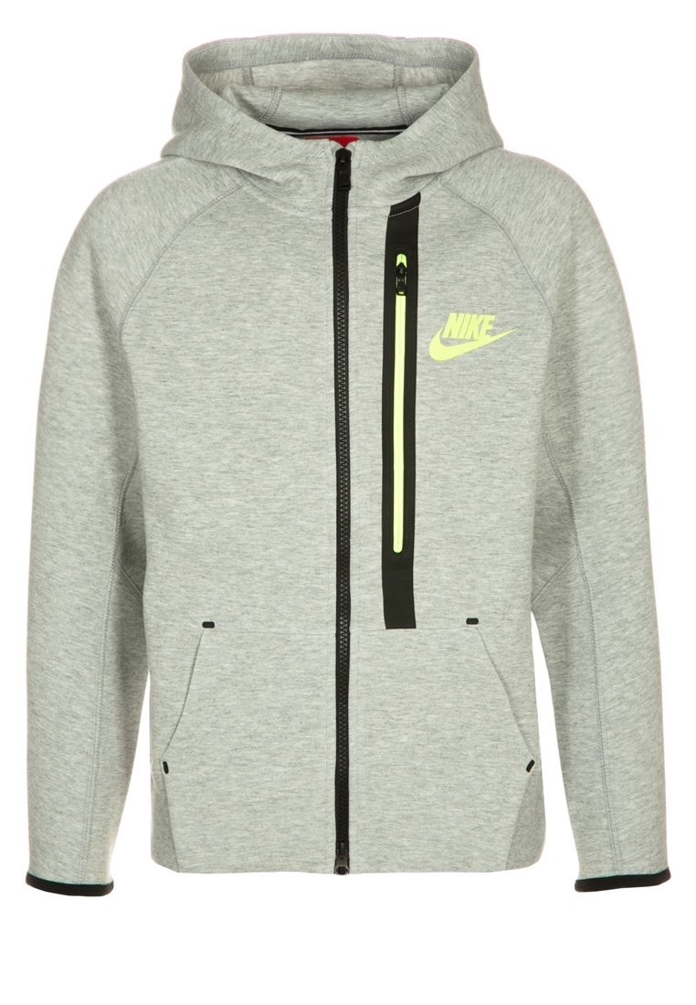 Grijs gewatteerd jack van zachte stof. Voorzien van een zwarte ritssluiting, twee steekzakken aan de voorkant en een neongele logo op de borst.