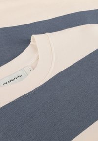 Sweatshirt rayé beige clair et bleu marine avec un col rond et un tissu texturé. L'étiquette indique "THE GOOPEOPLE" et la taille "L."