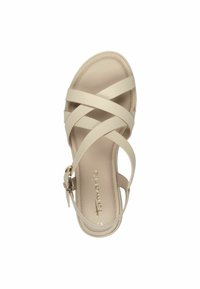 Beige szandál keresztbe futó pántokkal, bokapántos csattal és lapos talppal. Az insole-on aranybetűs felirat található. Az egész sima textúrájú.