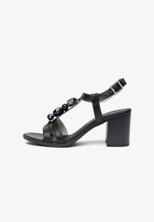 Zwarte leren sandaal met hak en enkelbandje, zilveren gesp, blokhak en decoratieve donkere marmerachtige kralen op het voorste bandje.
