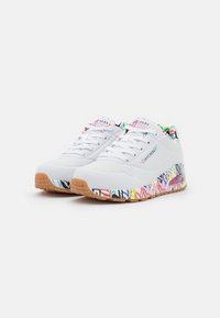 Weiße Sportschuhe mit perforiertem Obermaterial, buntem abstraktem Muster auf der Sohle und einer Außensohle aus Gummi. Schnürsenkel und gepolsterter Kragen sind sichtbar.