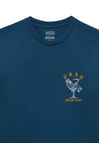Camiseta Vans azul oscuro con un pequeño gráfico de una Parca sosteniendo una bebida, sentada sobre una copa de martini, con el texto "Vans Speak Easy".