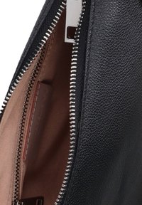 Interno di una borsa in pelle nera con fodera beige, dotata di una cerniera argentata e di un piccolo scomparto per carte o oggetti, superficie texture.