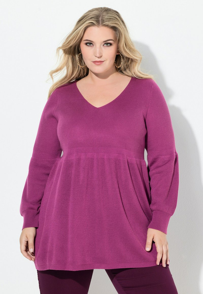 Dlouhý rukáv, tunika s V-výstřihem vyrobená z ribované pleteniny, s rozšířeným spodním lemem v hluboké magentové barvě. Volný střih s kalhotovými rukávy.