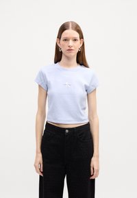 Jasnoniebieski krótki T-shirt wykonany z miękkiego materiału, z okrągłym dekoltem i krótkimi rękawami. Posiada małe białe logo z przodu.