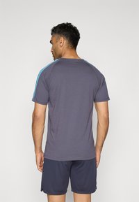 Grå kortærmet t-shirt med lyseblå detaljer på skuldrene, glat stof, afslappet pasform og ribbet crew neck. Båret med matchende shorts.