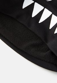 Zwarte fleece-gevoerde hoofdband met witte driehoekige tandpatronen. Zachte textuur met een snug fit, ontworpen voor warmte en comfort.