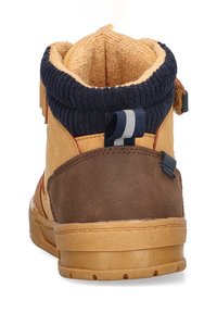 Botín de tobillo marrón y amarillo con un exterior texturizado, un cuello rígado en color navy y una suela de goma suave con un patrón de relieve mínimo.