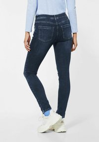 Mörkblå skinny jeans i denim, med midjehög midja, bakfickor och en slät, något texturerad yta.