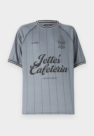 Szara koszula z krótkim rękawem z cienkimi pionowymi paskami, czarnym obszyciem na kołnierzu i rękawach oraz czarnym napisem „Jette's Cafeteria” i logo na piersi.