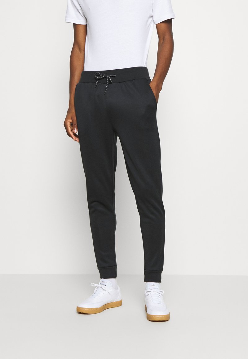 Pantaloni jogger neri con cintura regolabile e polsini alle caviglie. Realizzati in un materiale morbido, con tasche laterali e una texture liscia.