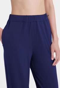 Pantaloni wide-leg blu navy realizzati in tessuto liscio, con vita elastica e tasche laterali, che offrono una vestibilità comoda e un design minimale.