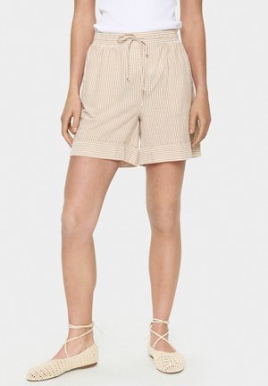 Beige and white striped shorts with an elastic waistband and drawstring. Features rolled cuffs and pockets. Paired with light-colored shoes.