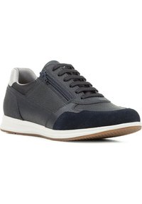 Zapatilla azul marino con cuero texturizado y ante, con cordones en la parte frontal y cremallera lateral. Entresuela blanca y suela de goma marrón.