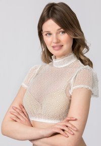 Weißes Spitzen-Crop-Top mit kurzen Ärmeln, das einen hohen Ausschnitt und kunstvolle Blumenmuster aufweist. Die Textur ist leicht und transparent.