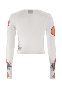 Witte cropped top met lange mouwen, versierd met bloemen- en geometrische patronen in rood en groen op de mouwen, gemaakt van lichtgewicht, doorschijnende stof.