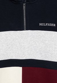 Bluza z kapturem zapinana na zamek, w kolorach granatowym, szarym i burgundowym, z haftowanym na biało napisem "HILFIGER".