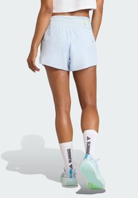 Svetlo modre športne kratke hlače z elastičnim pasom in dvema stranskima žepoma, kombinirane z belimi nogavicami s črnim napisom »RUNNING«.