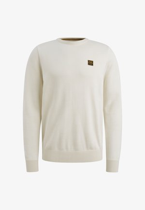 Suéter beige claro hecho de un material suave, con cuello redondo y puños acanalados. Una pequeña etiqueta negra está cosida en el pecho.