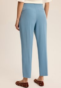 Jasnoniebieskie spodnie o dopasowanym kroju, proste nogawki i dwie tylne kieszenie, w połączeniu z bordowymi balerinami z złotymi akcentami.